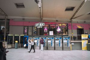 Off Beat Donut Co. café at Connolly Station in Dublin, with ticket machines in the foreground and commuters walking past in a busy transport hub.