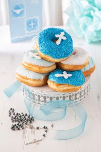 Blue and white Offbeat Donuts for Communion with cross toppers and sprinkles on a decorative stand