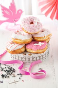 Pink and white Offbeat Donuts stacked for a Communion celebration with sprinkles, icing, and cross toppers